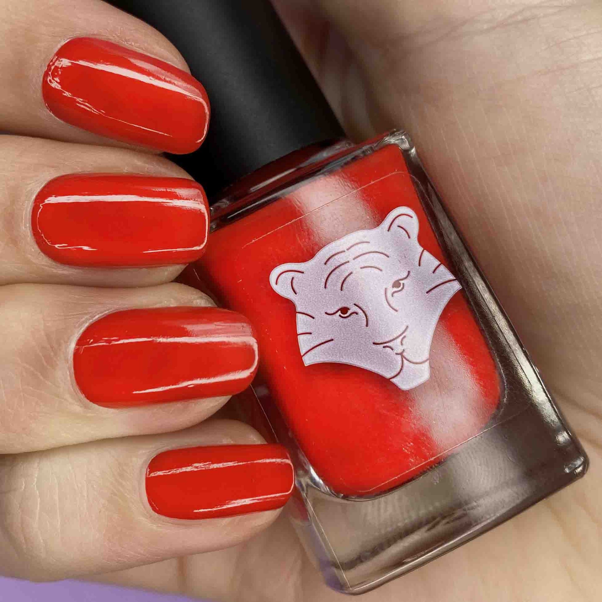 Vernis rouge oranger appliqué sur les ongles